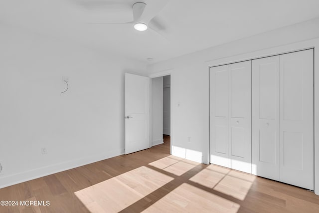 unfurnished bedroom with ceiling fan, a closet, and light wood-type flooring