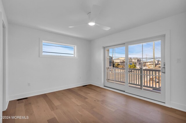 spare room with a healthy amount of sunlight, hardwood / wood-style floors, and ceiling fan