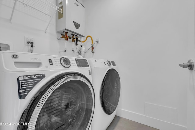 clothes washing area featuring washer and clothes dryer and water heater