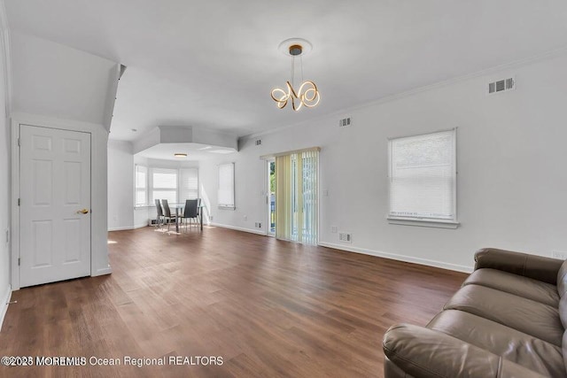 living room with dark hardwood / wood-style flooring, crown molding, and a chandelier