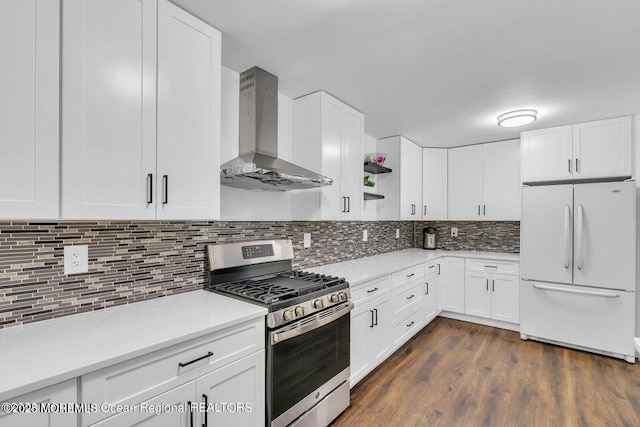 kitchen with stainless steel gas stove, white cabinetry, decorative backsplash, white refrigerator, and wall chimney exhaust hood