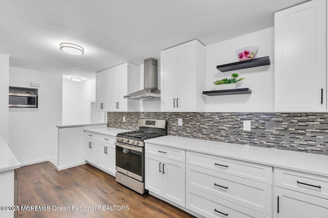 kitchen featuring white cabinets, appliances with stainless steel finishes, decorative backsplash, and wall chimney range hood