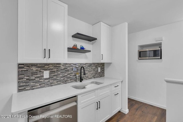 kitchen with appliances with stainless steel finishes, sink, white cabinets, dark hardwood / wood-style flooring, and backsplash