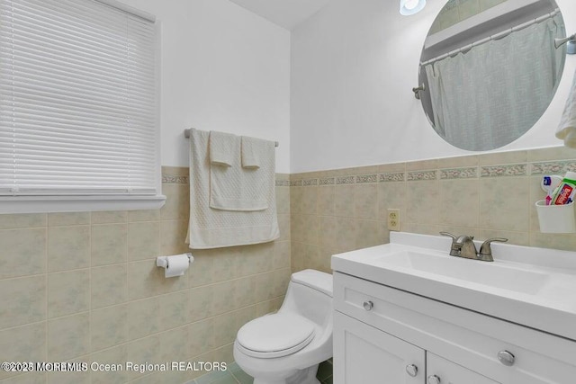 bathroom with vanity, tile walls, and toilet