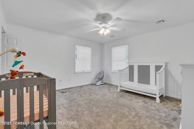 bedroom with a nursery area, carpet flooring, and ceiling fan