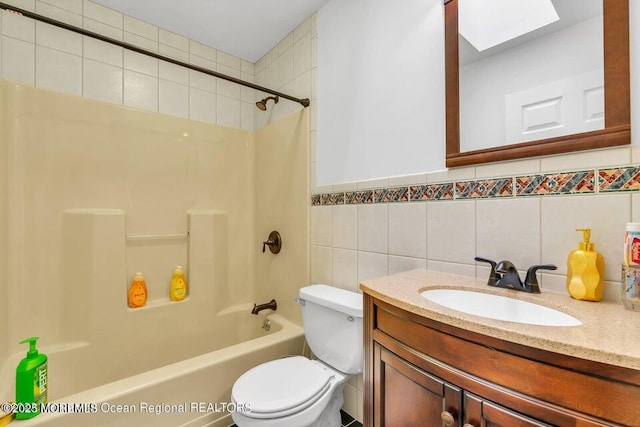 full bathroom with toilet, tiled shower / bath, a skylight, tile walls, and vanity