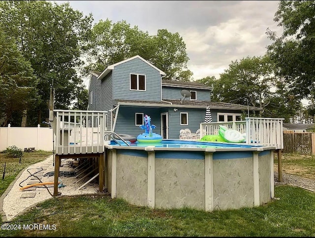 back of house with fence, a deck, and a fenced in pool