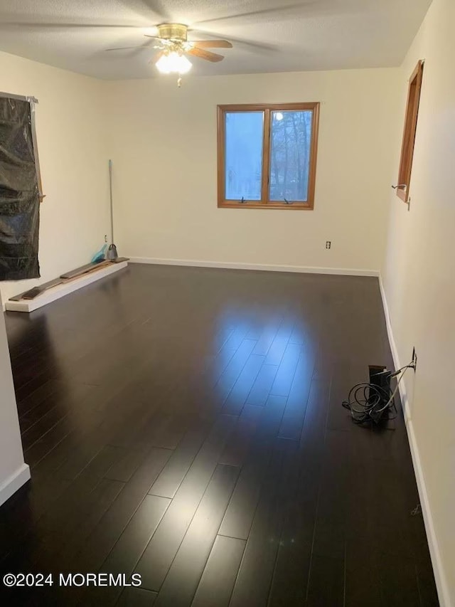 spare room featuring dark wood-type flooring and ceiling fan