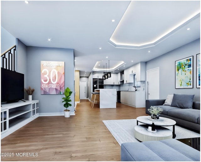 living room with a raised ceiling and light wood-type flooring