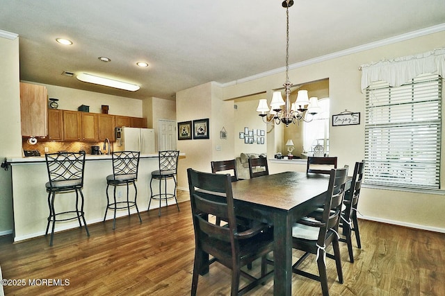 dining space featuring an inviting chandelier, ornamental molding, and dark hardwood / wood-style floors