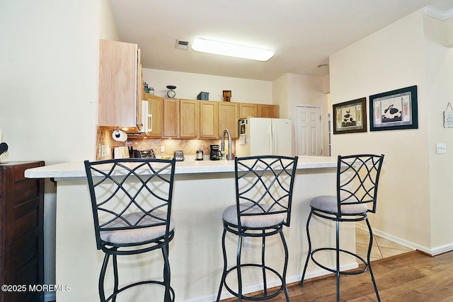 kitchen featuring tasteful backsplash, white appliances, dark wood-type flooring, and kitchen peninsula