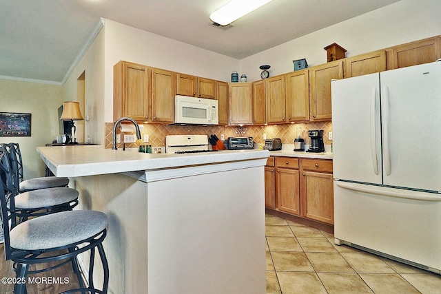 kitchen featuring sink, white appliances, light tile patterned floors, a kitchen bar, and decorative backsplash