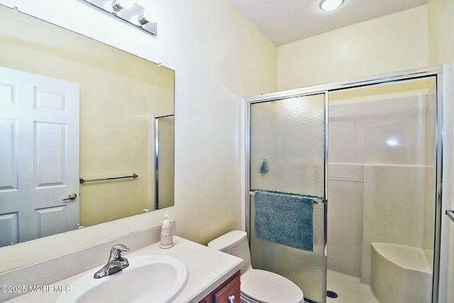 bathroom with vanity, a shower with door, and toilet