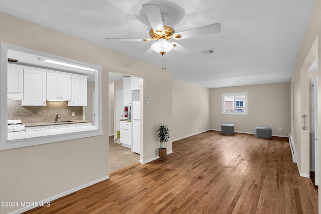 kitchen featuring tasteful backsplash, sink, white cabinets, hardwood / wood-style flooring, and ceiling fan