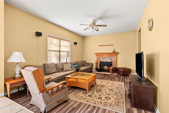 living room with a tiled fireplace, hardwood / wood-style flooring, and ceiling fan