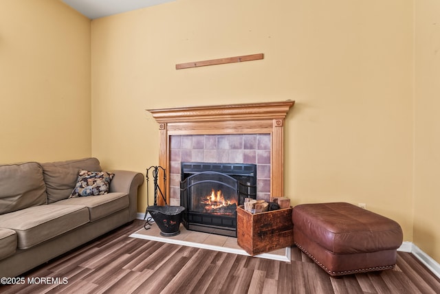 living room featuring a tiled fireplace and wood-type flooring