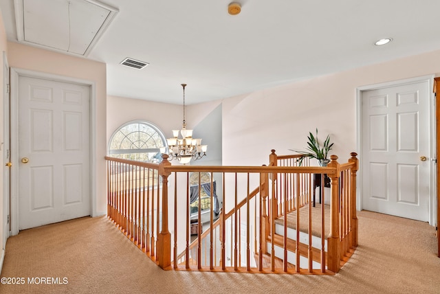 corridor with a notable chandelier and light colored carpet