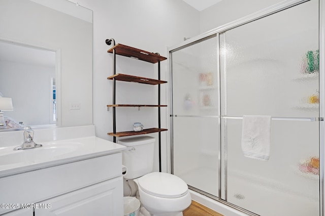 bathroom with vanity, a shower with door, and toilet