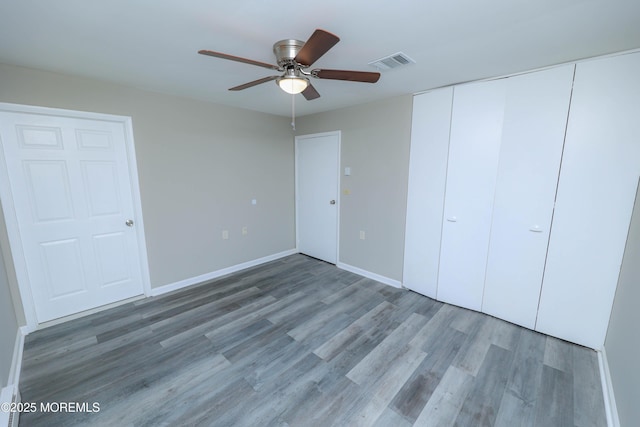 unfurnished bedroom featuring hardwood / wood-style flooring, ceiling fan, and a closet