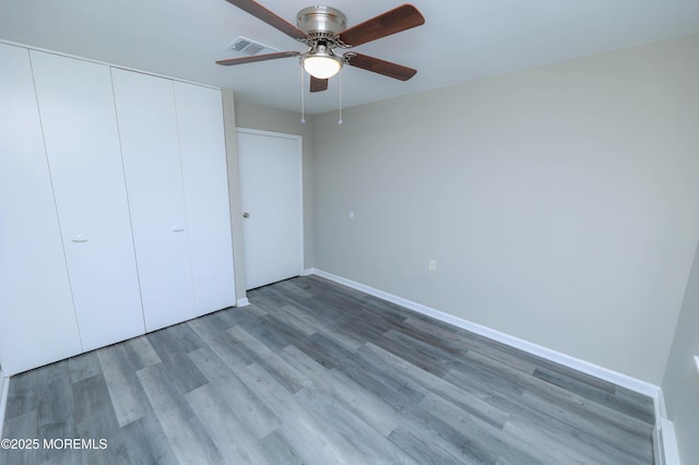 unfurnished bedroom with hardwood / wood-style flooring, ceiling fan, and a closet