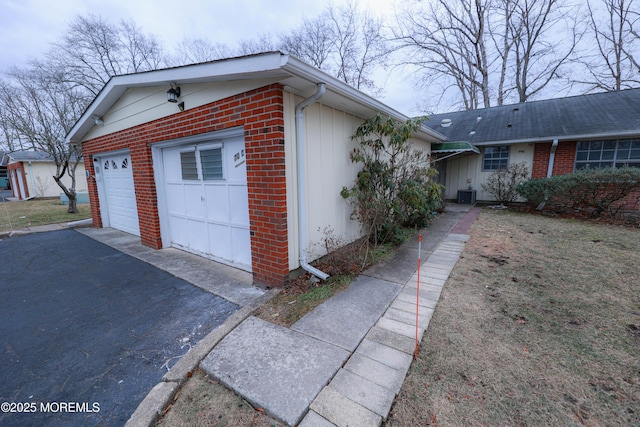 view of home's exterior with driveway, a garage, cooling unit, and brick siding