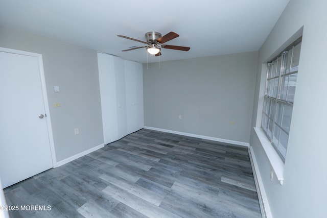 spare room featuring hardwood / wood-style floors, ceiling fan, and a baseboard heating unit