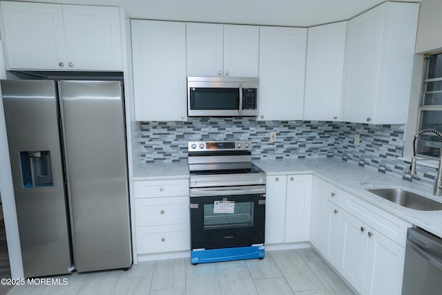 kitchen with sink, white cabinetry, stainless steel appliances, light stone counters, and tasteful backsplash