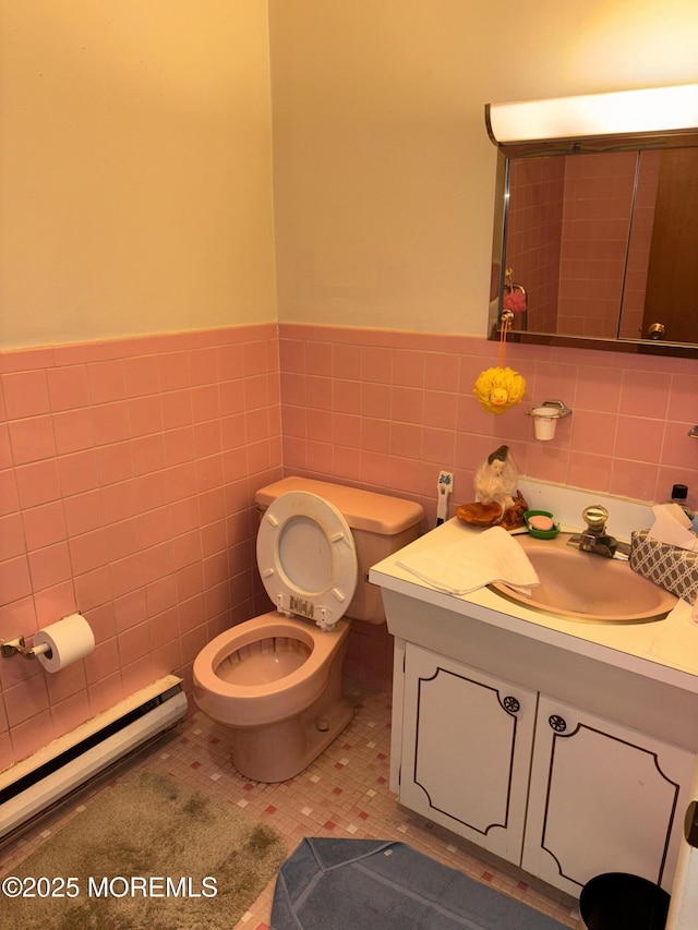 bathroom with a baseboard radiator, tile walls, vanity, and toilet