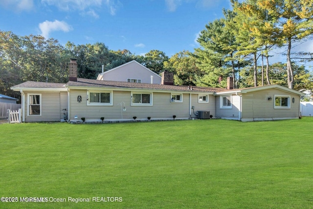 rear view of property with central AC and a lawn