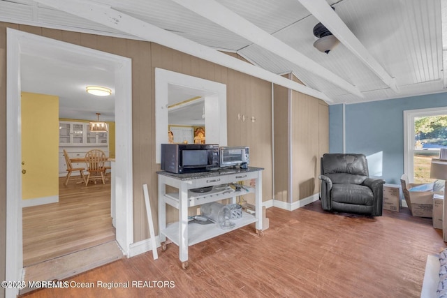 living area featuring wood-type flooring, lofted ceiling with beams, and wood walls