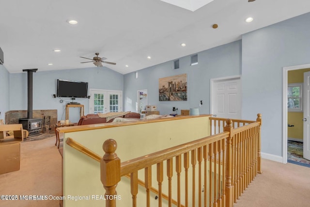 interior space with a wealth of natural light, lofted ceiling with skylight, ceiling fan, and a wood stove