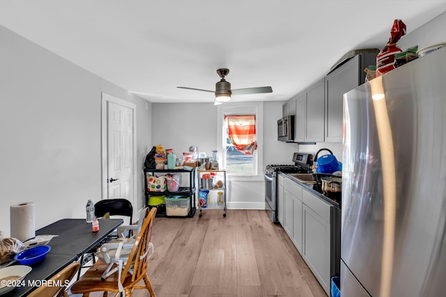 kitchen featuring gray cabinets, light hardwood / wood-style floors, ceiling fan, and appliances with stainless steel finishes