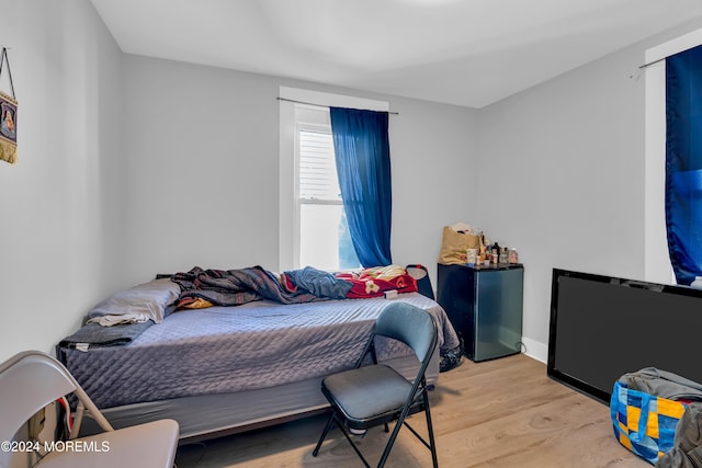 bedroom featuring fridge and light hardwood / wood-style floors