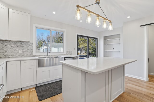 kitchen featuring white cabinetry, a center island, pendant lighting, and light hardwood / wood-style flooring