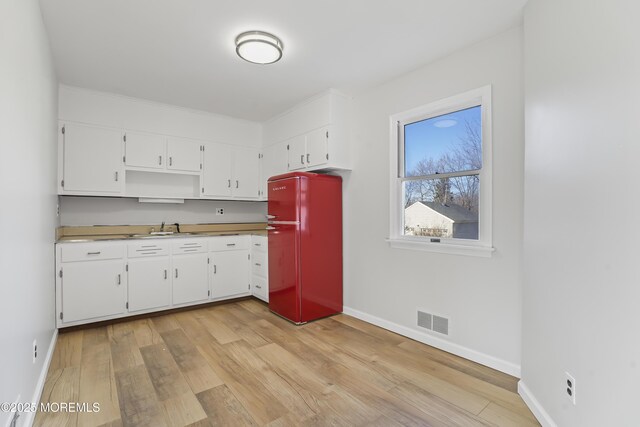 kitchen with sink, fridge, light hardwood / wood-style floors, and white cabinets