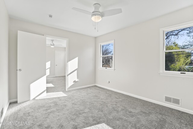 unfurnished bedroom with multiple windows, light colored carpet, and ceiling fan