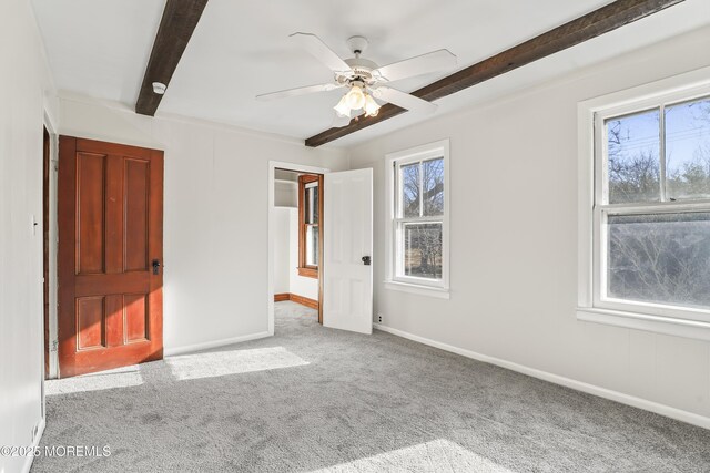 unfurnished bedroom featuring beamed ceiling, light colored carpet, ceiling fan, and multiple windows