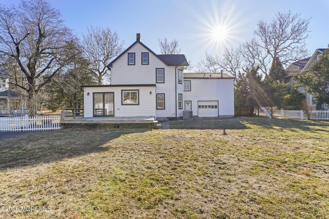 rear view of house with a garage, a wooden deck, cooling unit, and a lawn