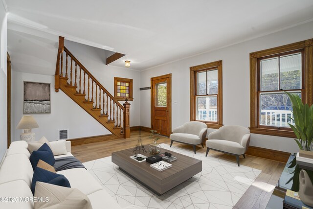 living room with crown molding and light hardwood / wood-style floors