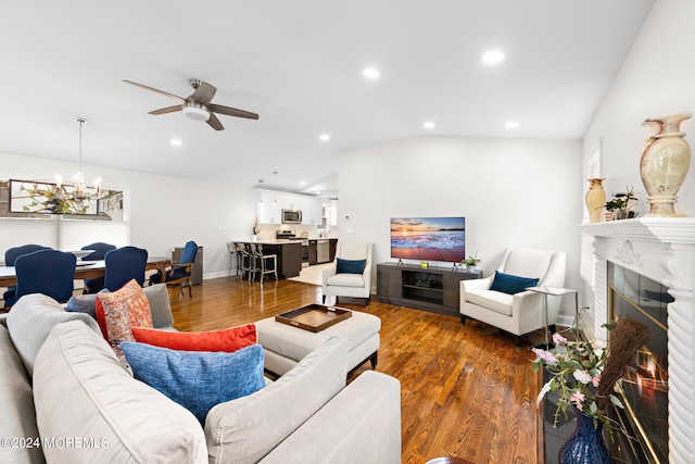 living room featuring vaulted ceiling, ceiling fan with notable chandelier, and dark hardwood / wood-style flooring