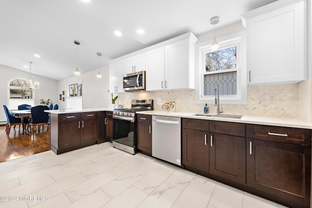 kitchen featuring appliances with stainless steel finishes, kitchen peninsula, sink, and hanging light fixtures