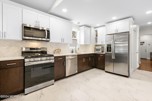 kitchen with sink, dark brown cabinets, stainless steel appliances, white cabinets, and decorative backsplash