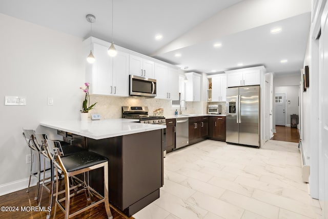 kitchen with appliances with stainless steel finishes, a breakfast bar, pendant lighting, white cabinets, and kitchen peninsula