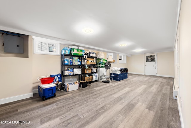 basement featuring baseboard heating, electric panel, and hardwood / wood-style floors