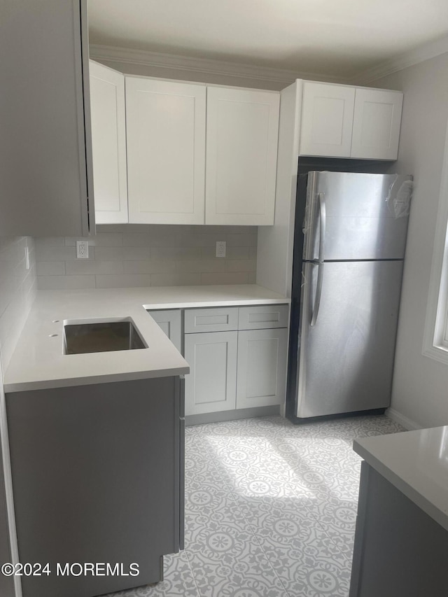 kitchen with sink, gray cabinetry, white cabinetry, tasteful backsplash, and stainless steel refrigerator