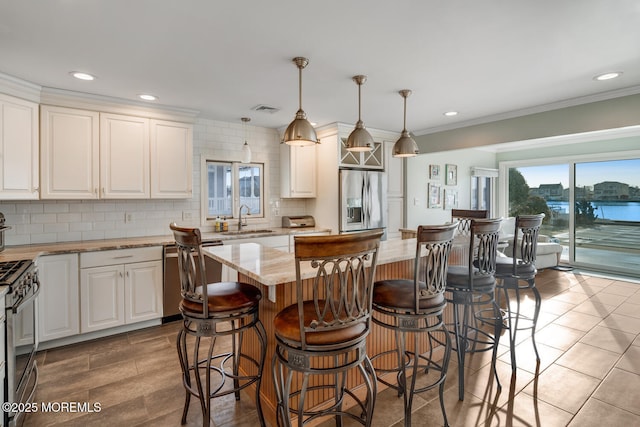 kitchen with appliances with stainless steel finishes, pendant lighting, sink, a center island, and light stone counters