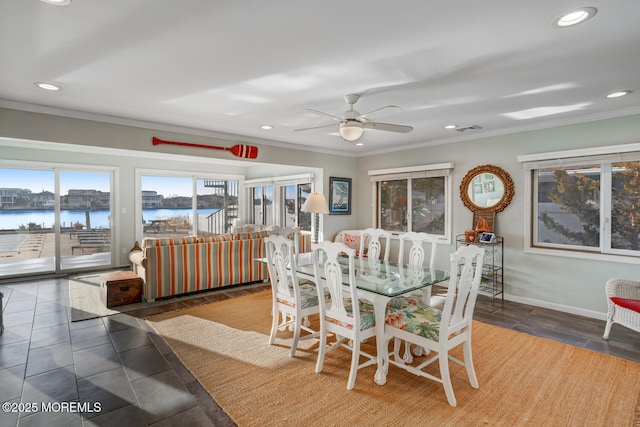 dining area with ornamental molding, ceiling fan, and a water view