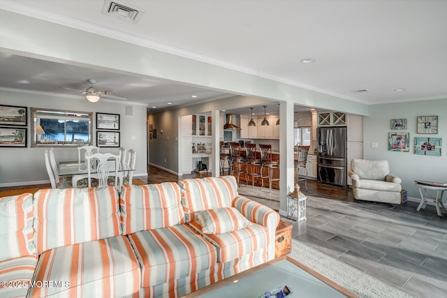 living room featuring ornamental molding, bar area, and ceiling fan