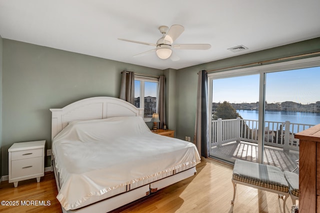 bedroom featuring a water view, ceiling fan, light hardwood / wood-style flooring, and access to outside