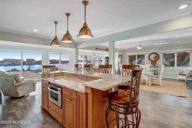 kitchen featuring a kitchen bar, decorative light fixtures, oven, and a water view